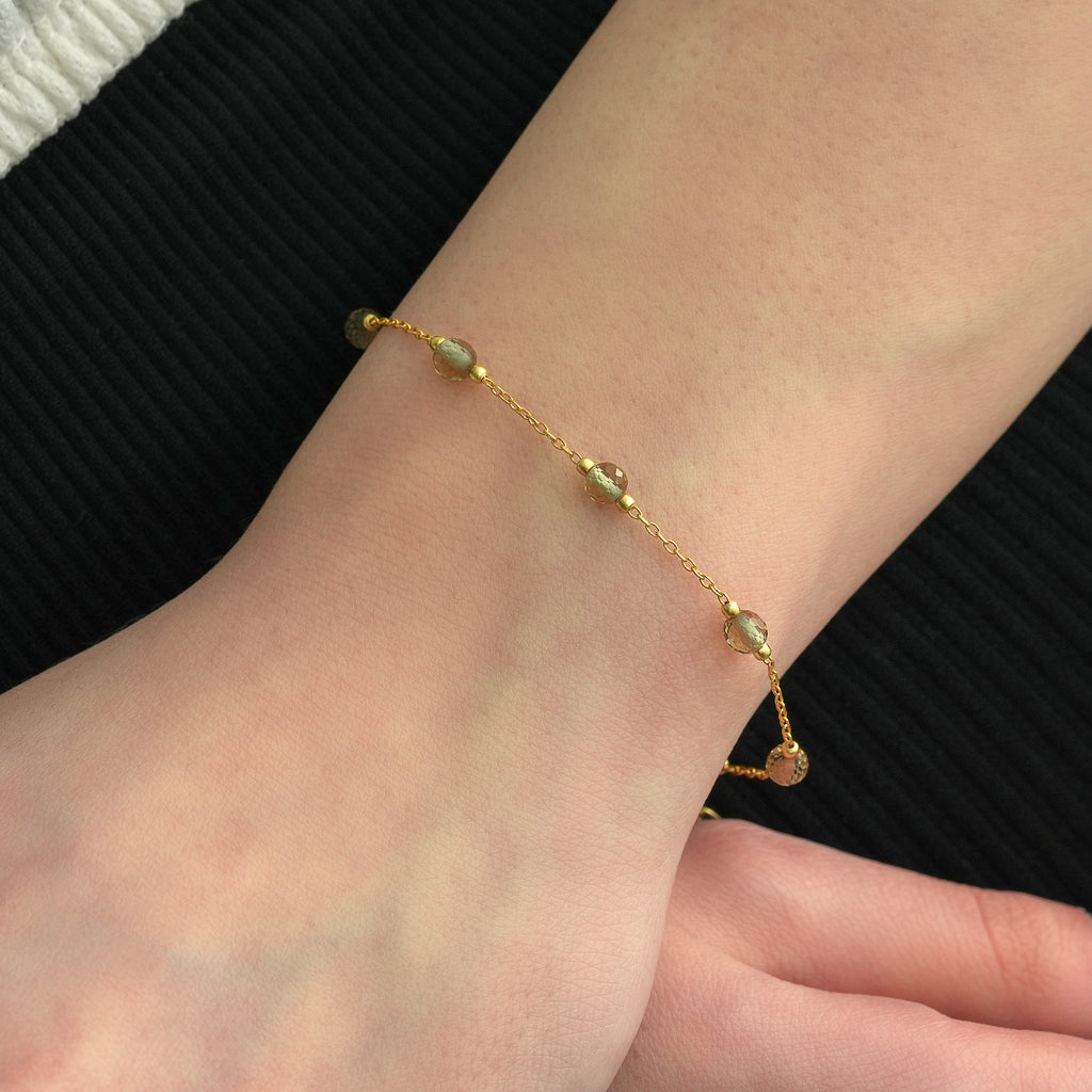 Close-up view of a delicate 14K gold plated bracelet featuring faceted color changing gemstones on a fine chain.