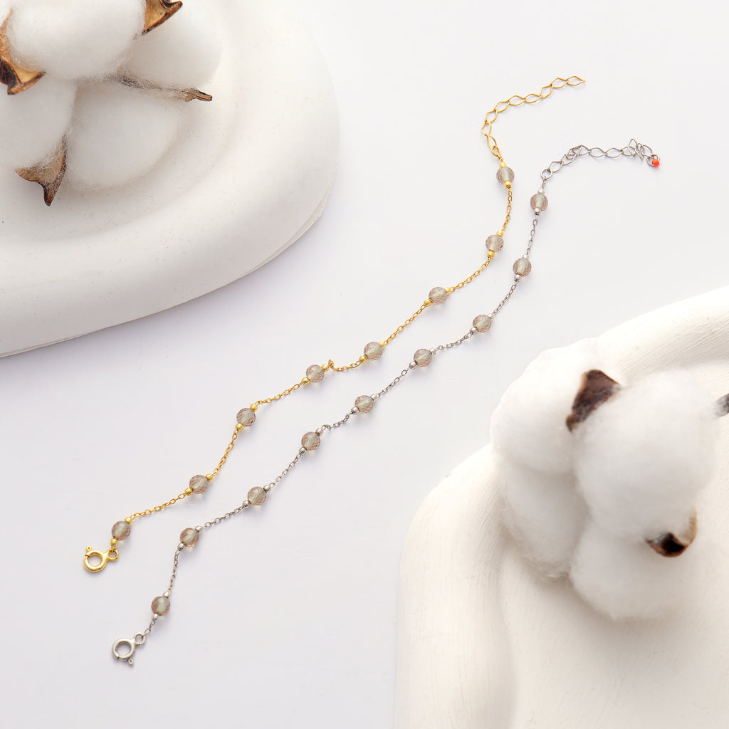 925 sterling silver 14K gold plated bracelet featuring faceted color changing gemstones on a delicate chain displayed on a white background with cotton decor.