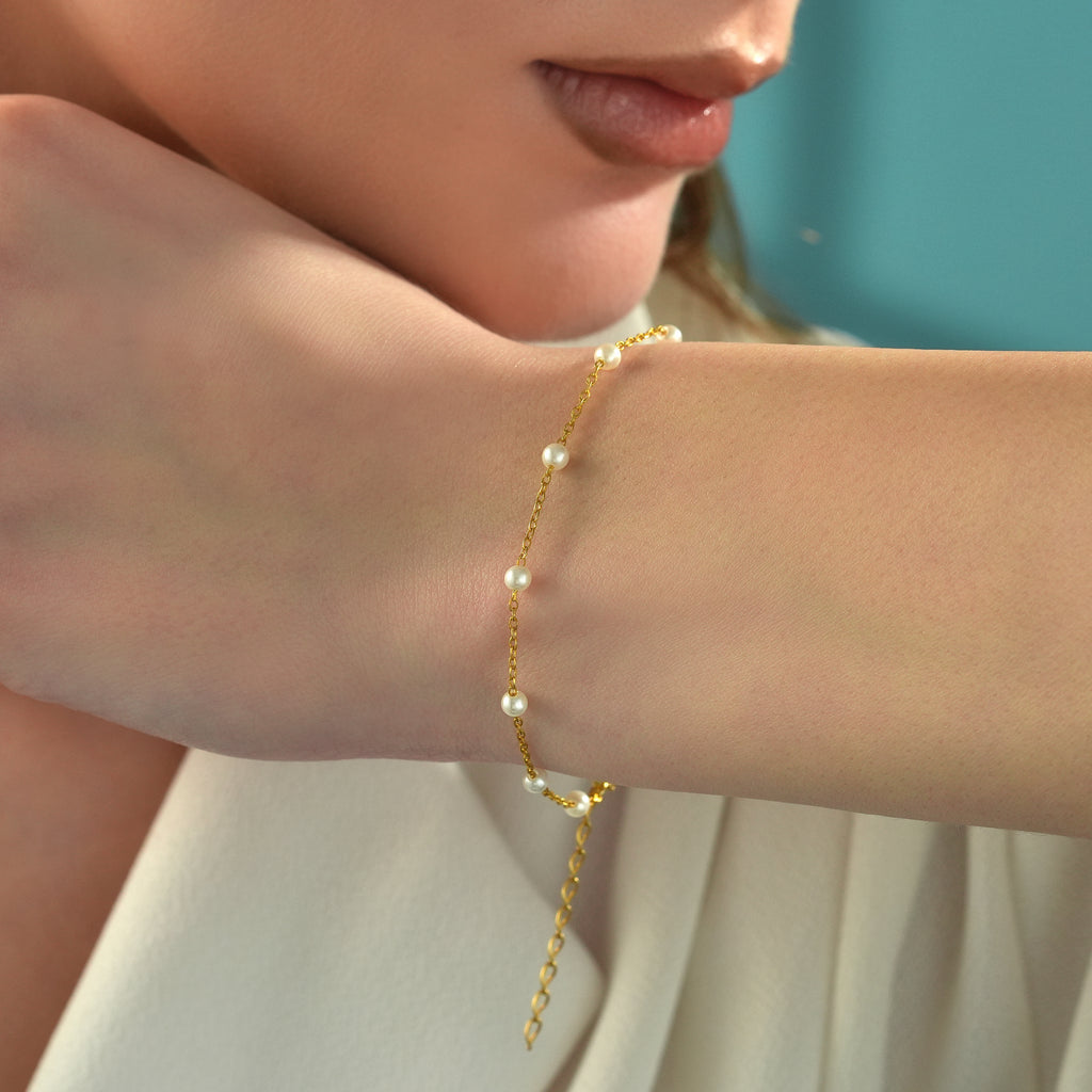 Minimalist 14K gold plated sterling silver pearl bracelet with dainty white pearls and adjustable extension chain, worn on a woman's wrist.