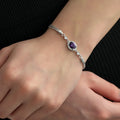 Close-up of a 925 sterling silver bracelet featuring an oval amethyst color cubic zirconia stone surrounded by clear CZ accents.