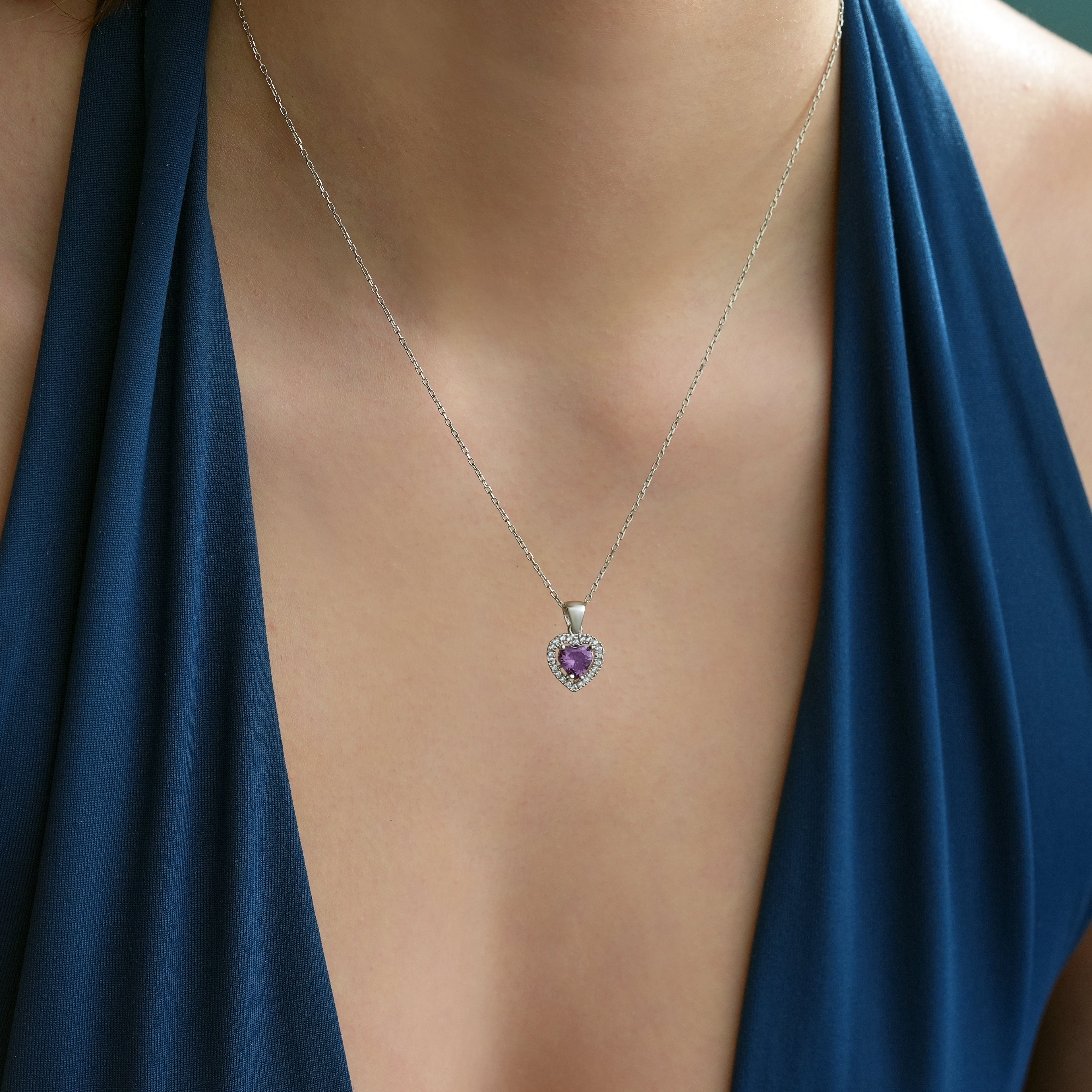 Close-up of a 925 sterling silver heart necklace with an amethyst color heart-shaped cubic zirconia surrounded by clear CZ halo stones.