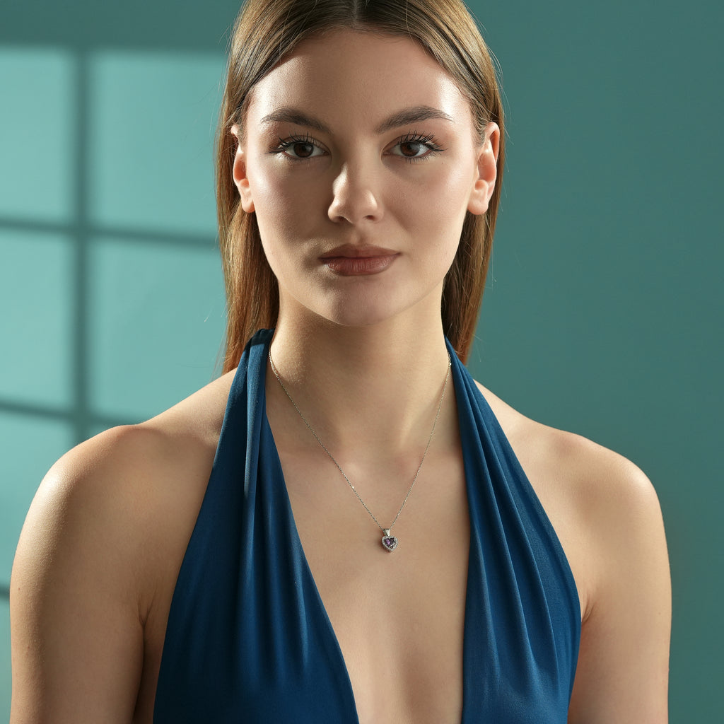 Woman wearing a 925 sterling silver heart pendant necklace with an amethyst color heart-shaped cubic zirconia and clear CZ halo accents.