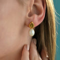 Close-up of 925 sterling silver gold plated drop earrings featuring faceted natural diaspore stones above genuine freshwater pearls.