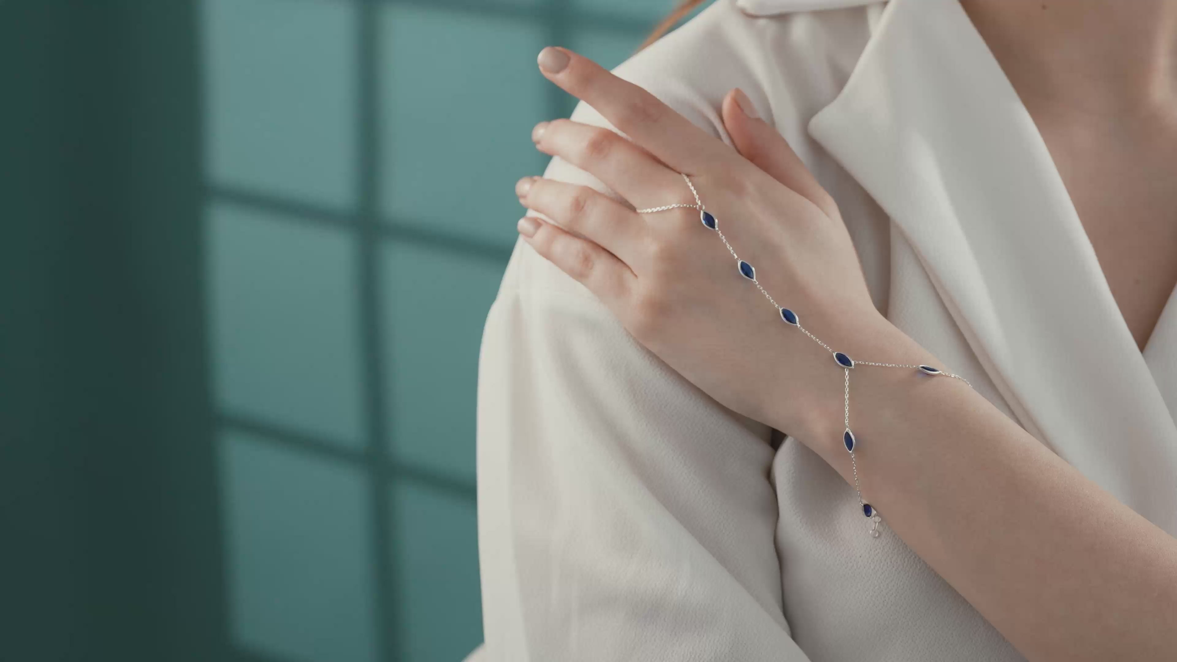 Video of Close-up of a 925 sterling silver hand chain bracelet featuring bezel-set marquise blue sapphire gemstones on a delicate adjustable chain.