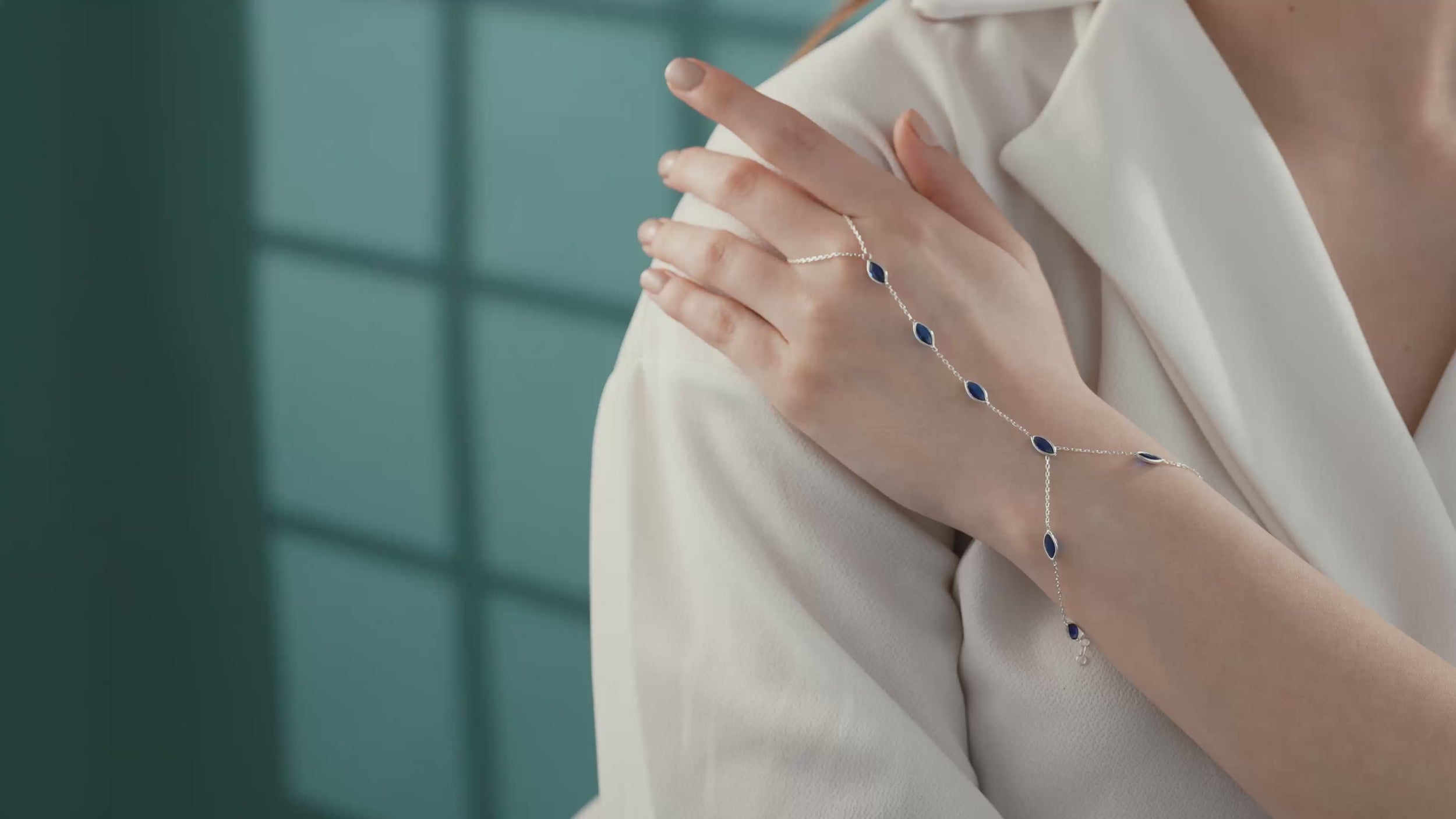 Video of Close-up of a 925 sterling silver hand chain bracelet featuring bezel-set marquise blue sapphire gemstones on a delicate adjustable chain.