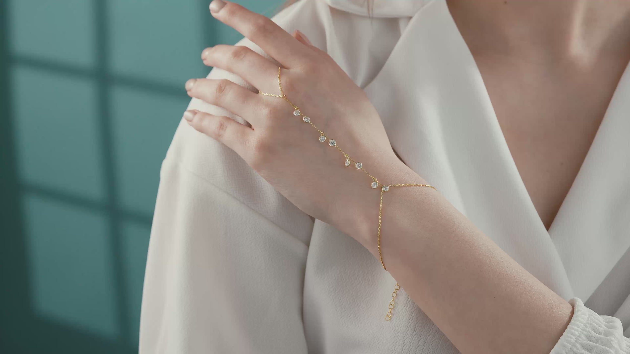 Video of Woman wearing a minimalist 14K gold plated 925 sterling silver hand chain bracelet with dangling round clear cubic zirconia stones.