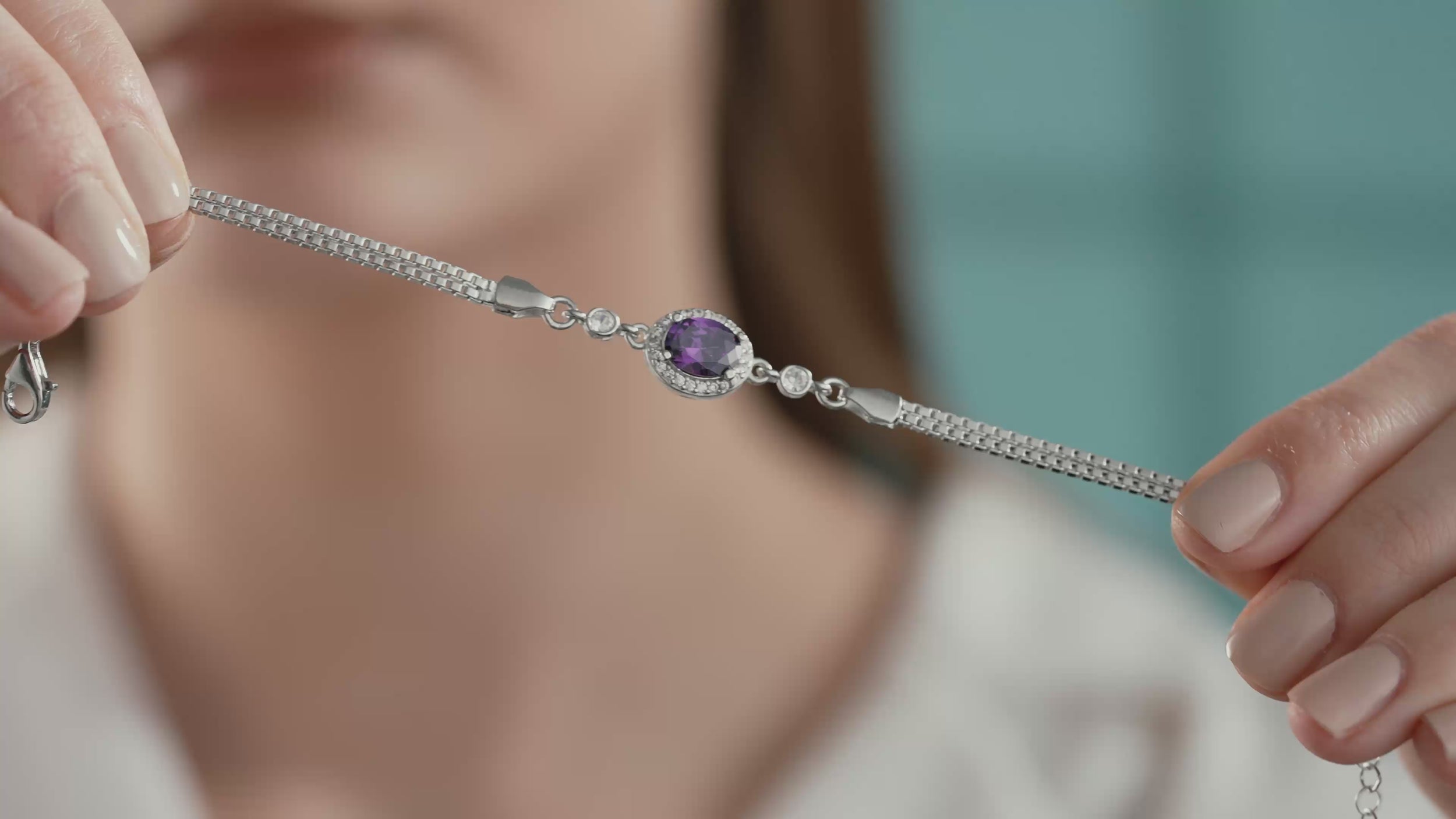 Video of Close-up of a 925 sterling silver bracelet featuring an oval amethyst color cubic zirconia stone surrounded by clear CZ accents.